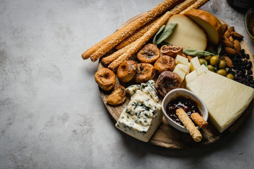 A rustic charcuterie board featuring cheese, dried figs, olives, and breadsticks for an elegant food presentation.