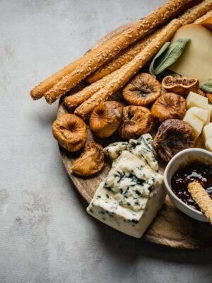 A rustic charcuterie board featuring cheese, dried figs, olives, and breadsticks for an elegant food presentation.