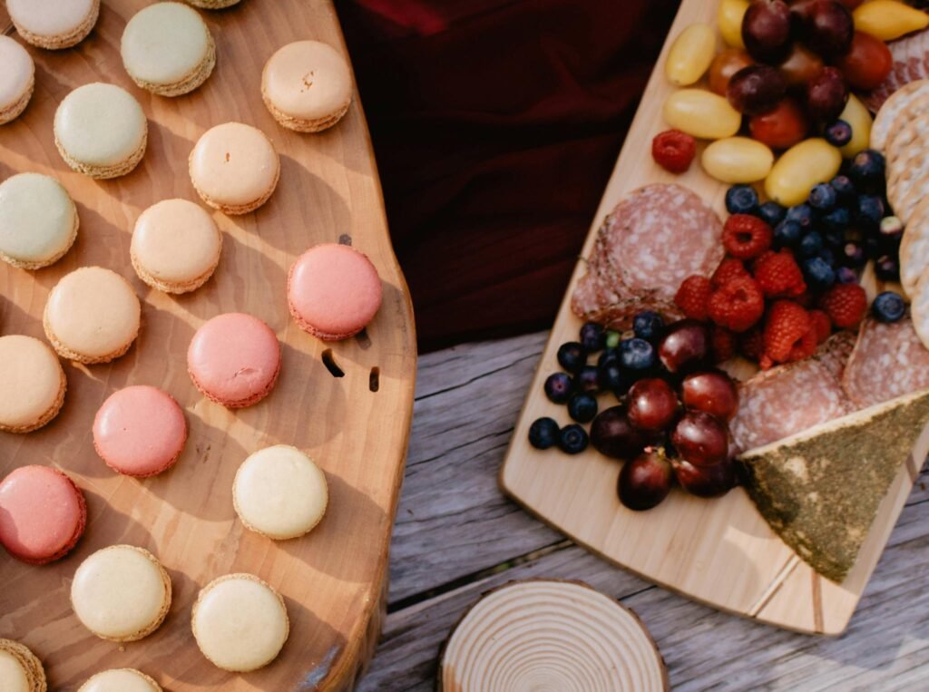 A top view of a charcuterie board with fresh fruits and macarons, perfect for gatherings.