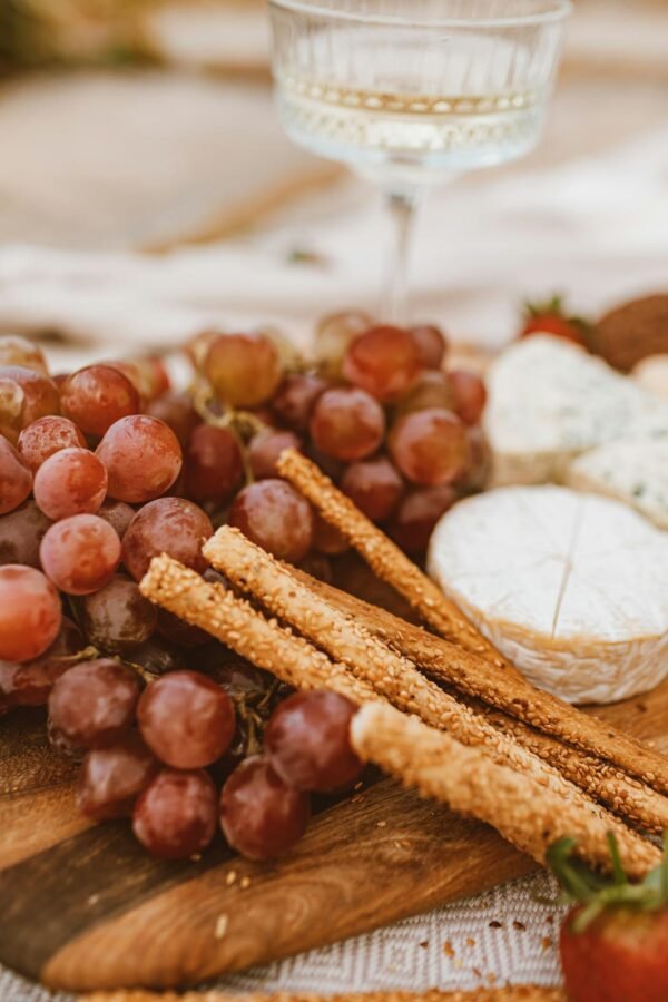 An artistic still life featuring cheese, grapes, and crackers on a wooden board. Perfect for rustic culinary themes.