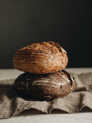 Freshly baked artisan sourdough loaves stacked on a rustic table setting.